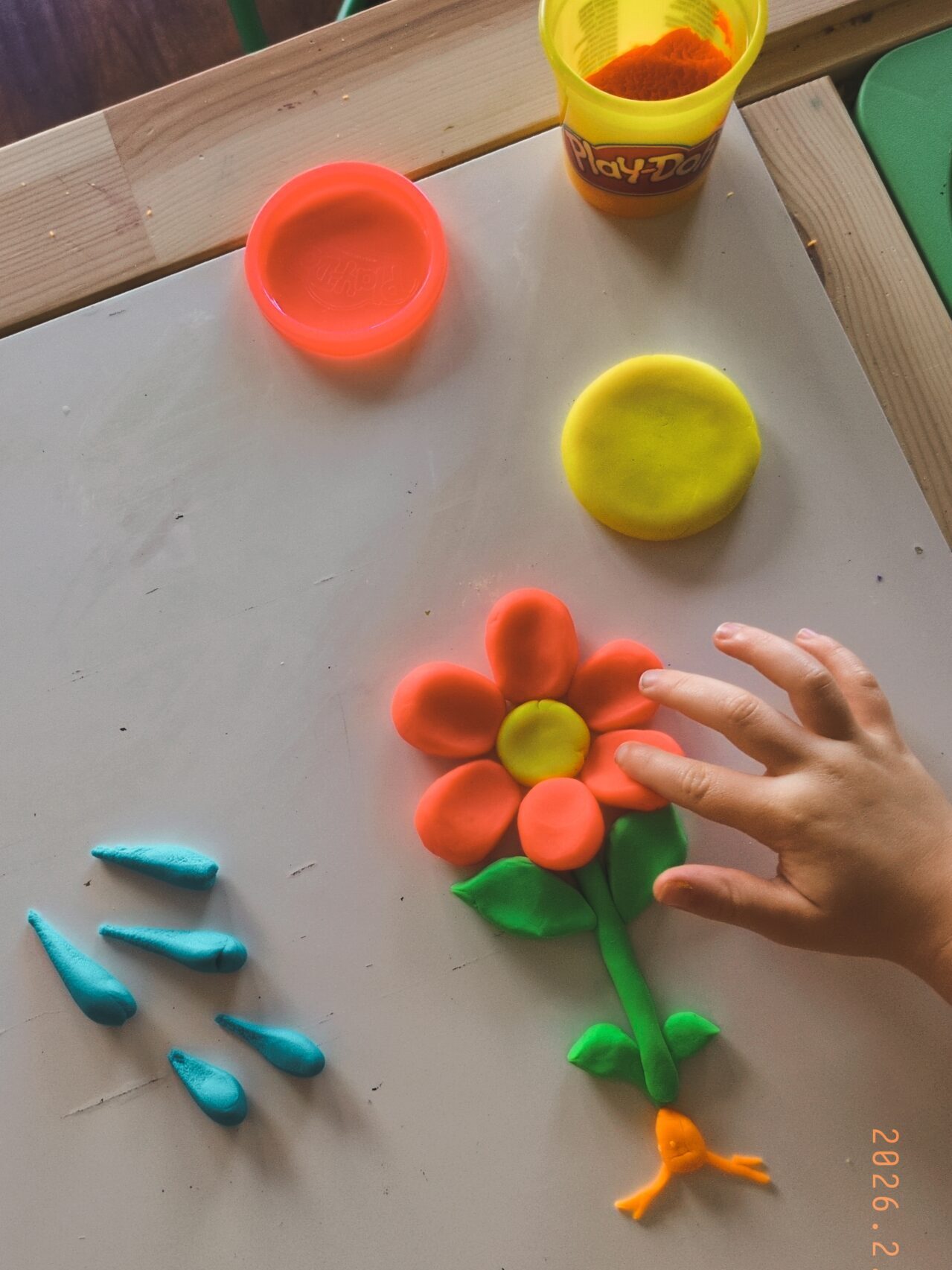 toddler hand looking at a play-doh flower