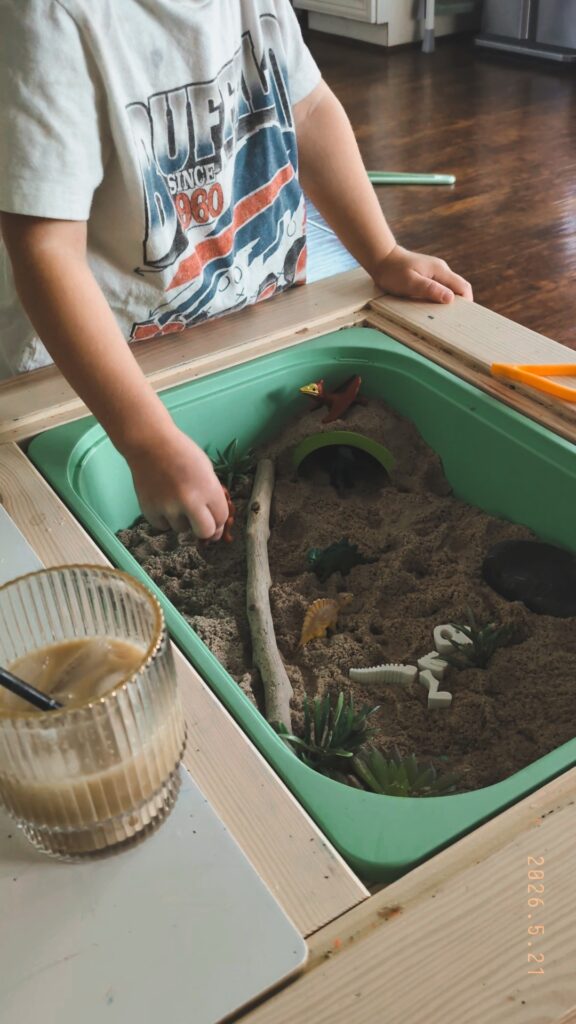 toddler boy playing with a dinosaur sensory bin