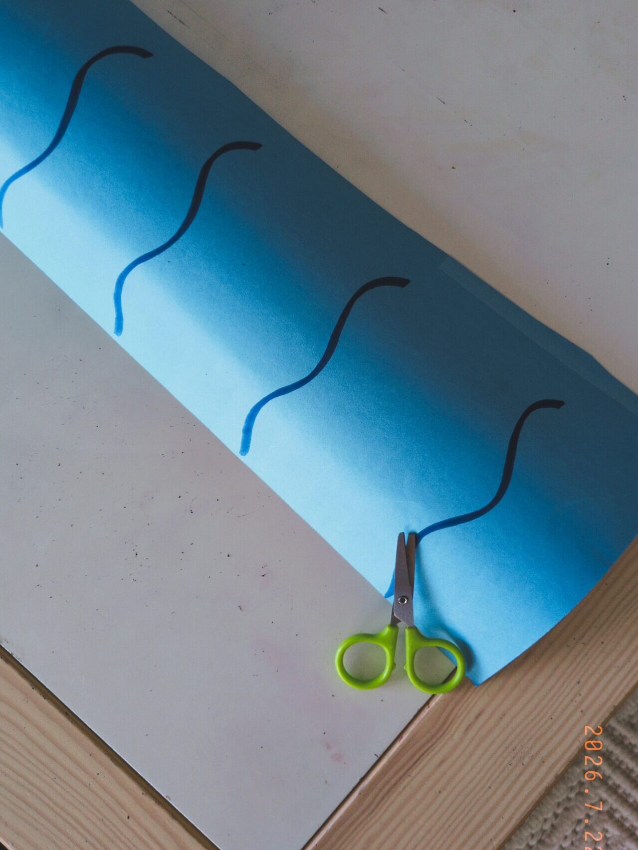 scissors laying on top of ocean waves drawn on blue paper