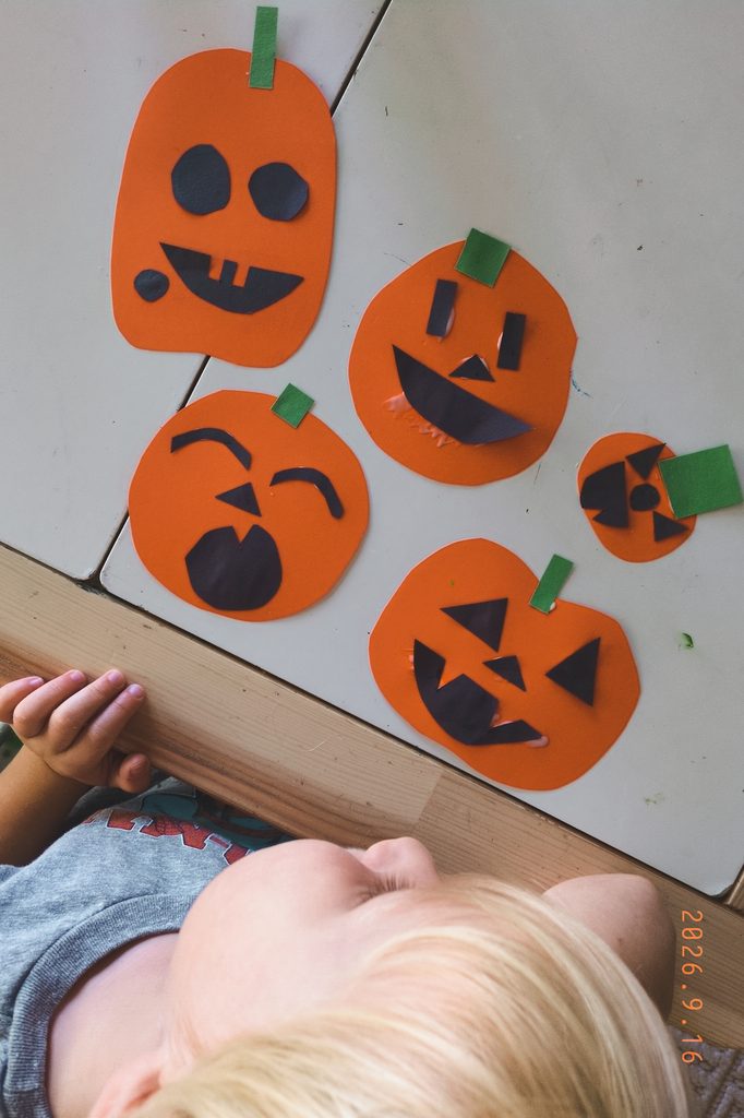 boy looking at his paper pumpkin jack-o'-lanterns